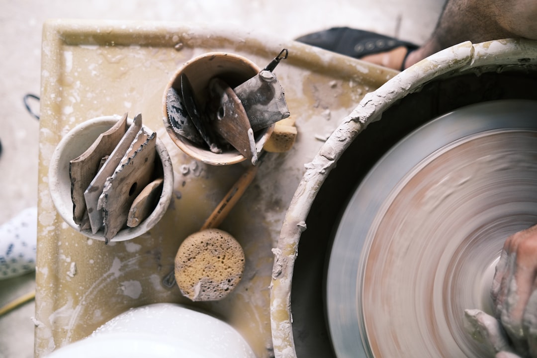 ceramicist trimming the foot of a stoneware vessel on a banding wheel in a natural-light studio
