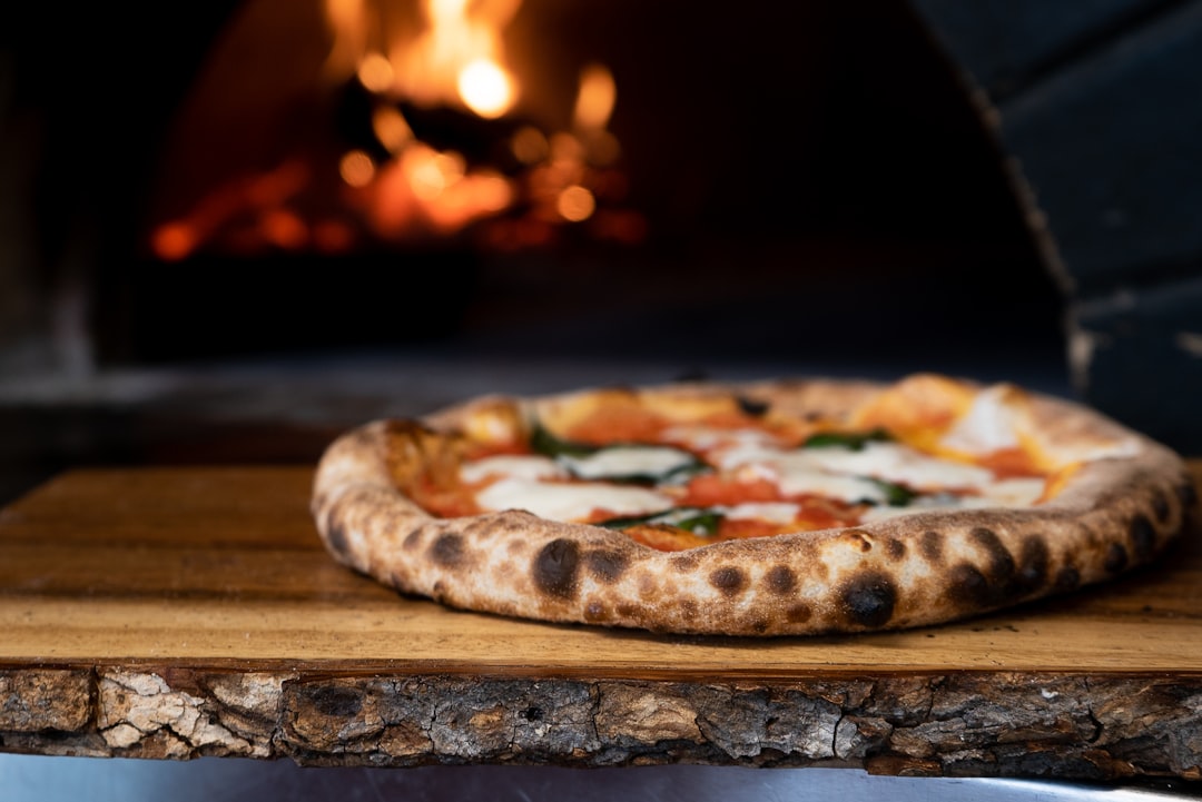 freshly baked Neapolitan pizza emerging from a wood-fired oven with charred leopard-spotted crust