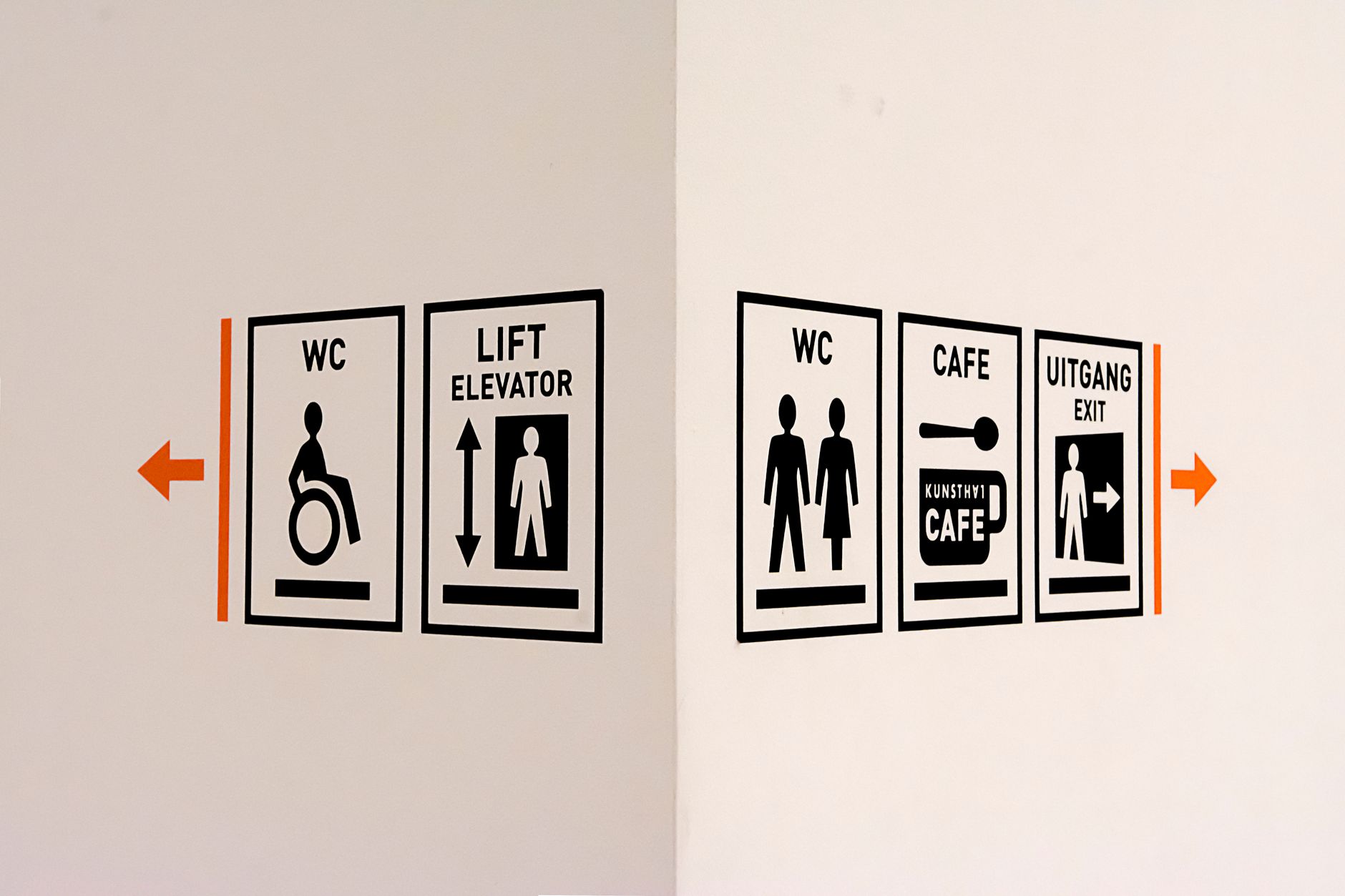 modern wayfinding signage system with colorful arrows and bold sans serif typography in cultural center hallway