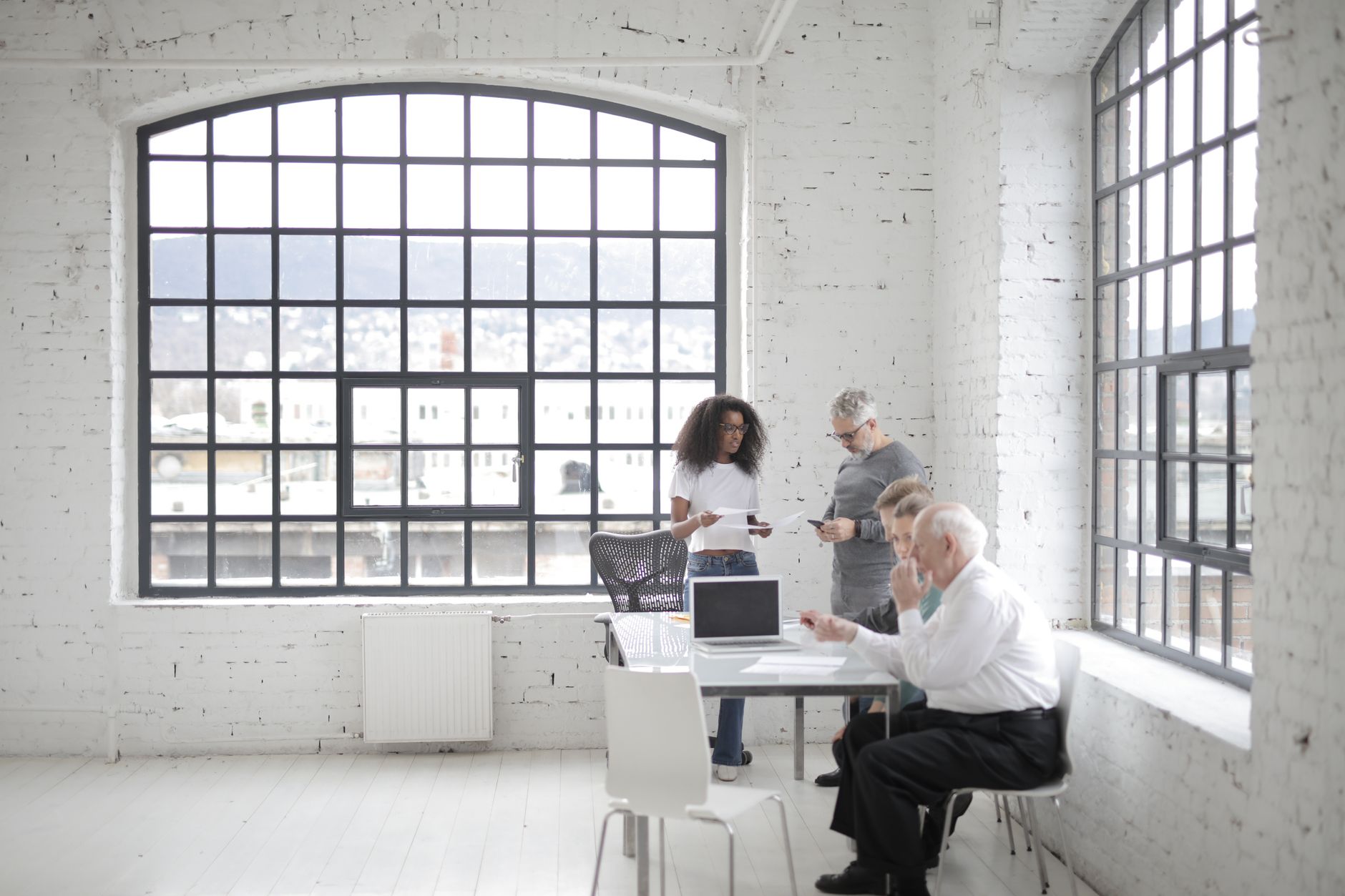 bright minimalist real estate office with exposed concrete walls large windows and team working around clean oak table