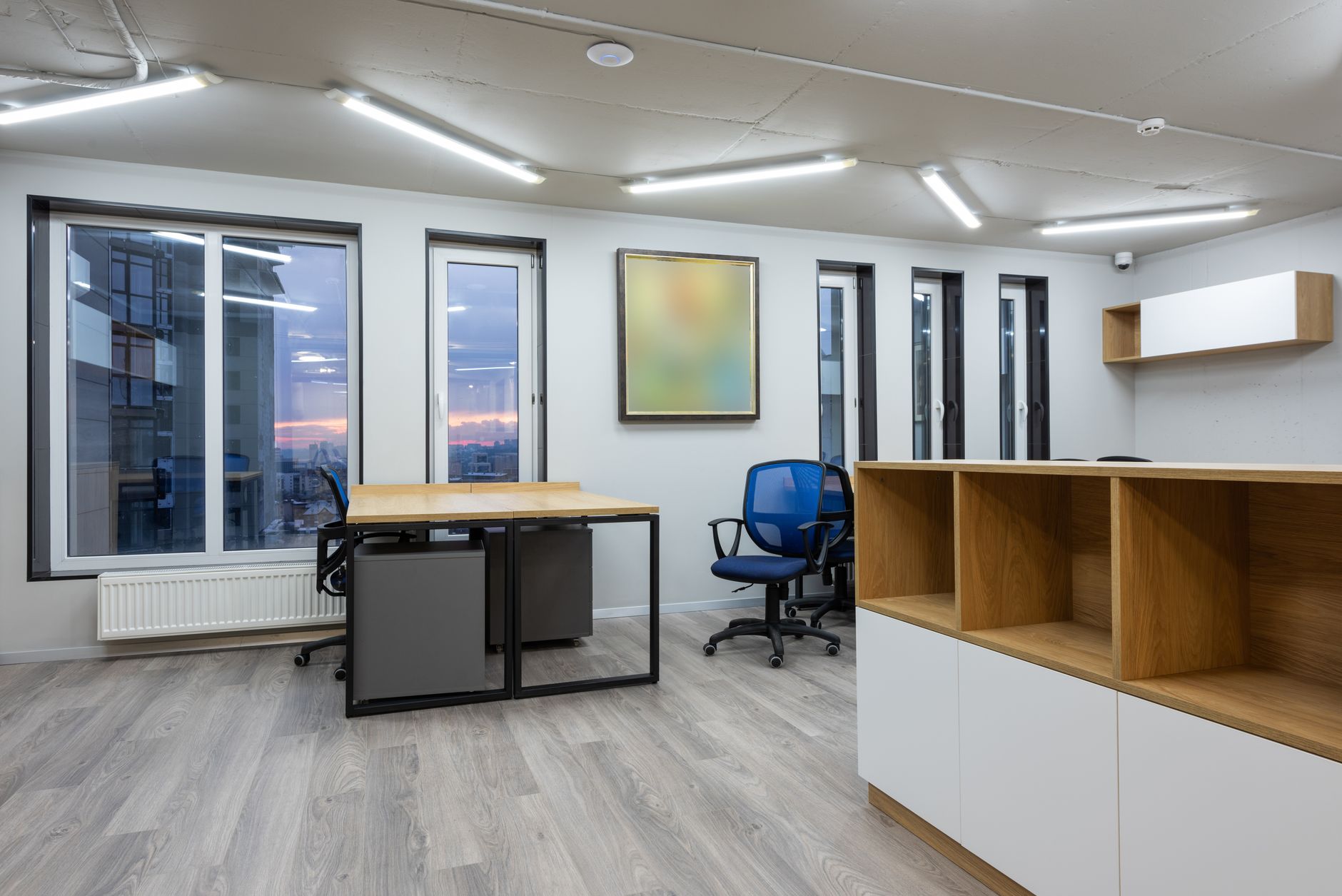 minimalist real estate office interior with natural light white oak desk and architectural property photography on walls