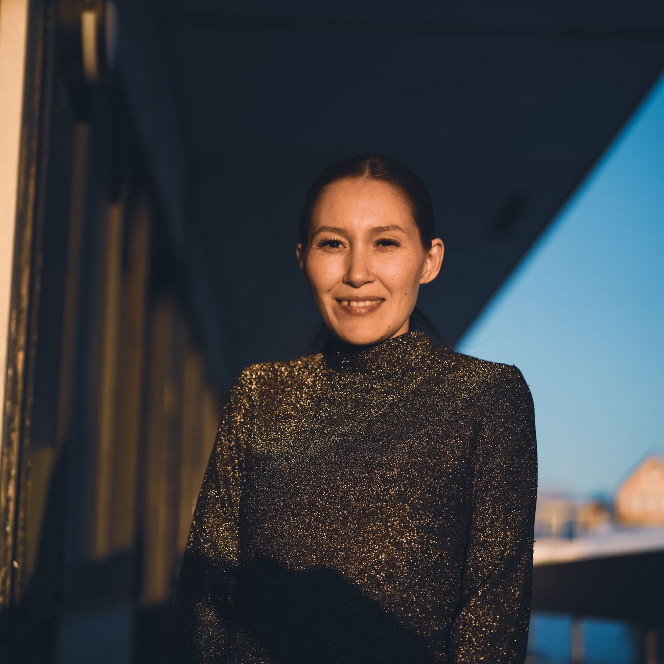 professional headshot of female real estate agent standing outdoors in front of contemporary California home with warm light