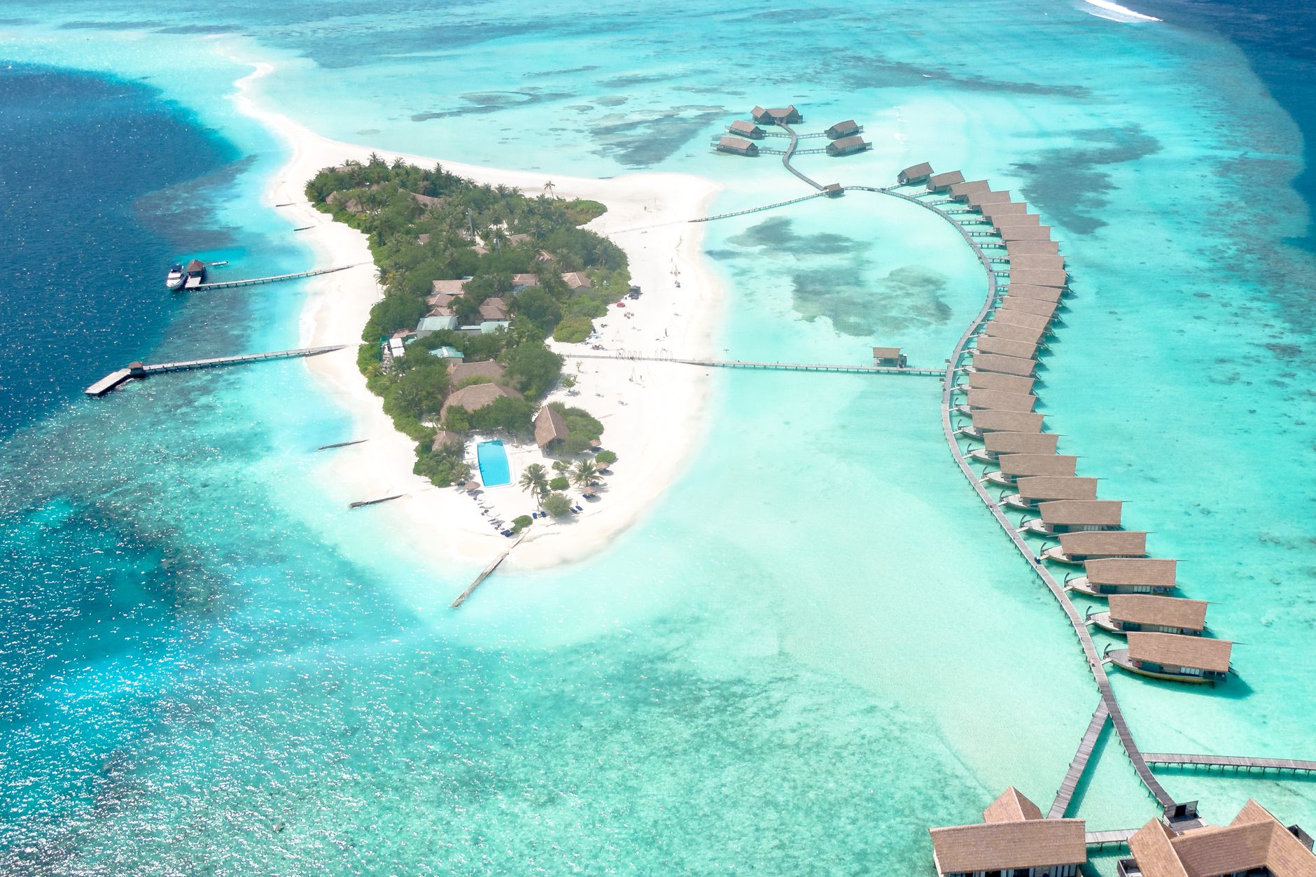 aerial view of secluded private island resort with overwater villas lush tropical gardens and turquoise lagoon