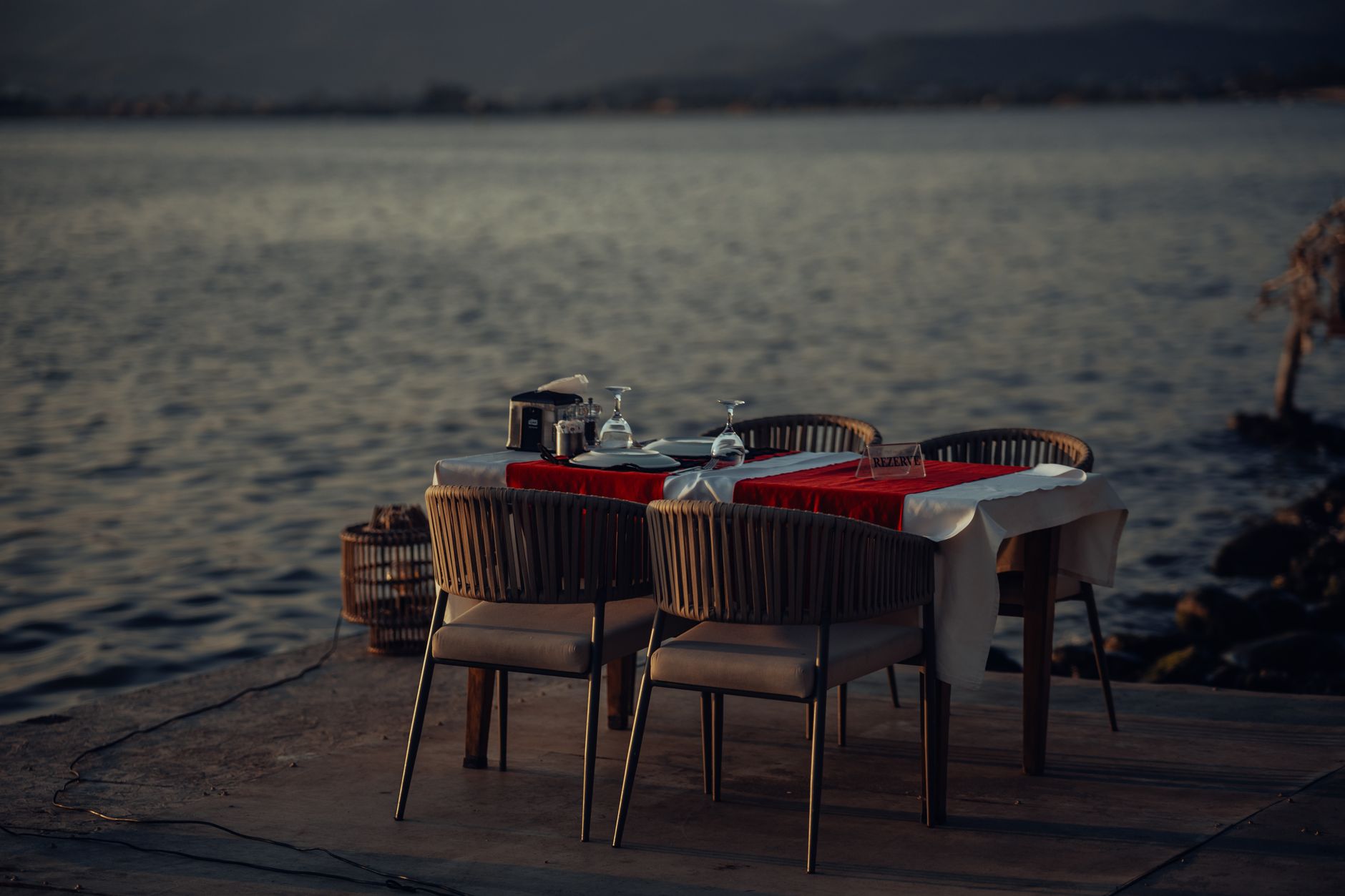 private villa terrace at dusk with candlelit dinner table set for two overlooking calm tropical sea
