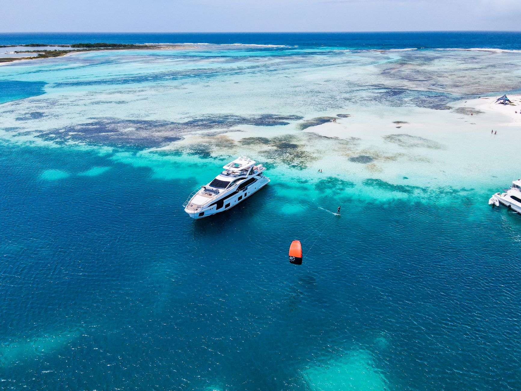 luxury resort private yacht at anchor in crystal clear lagoon with tropical island silhouette at golden hour
