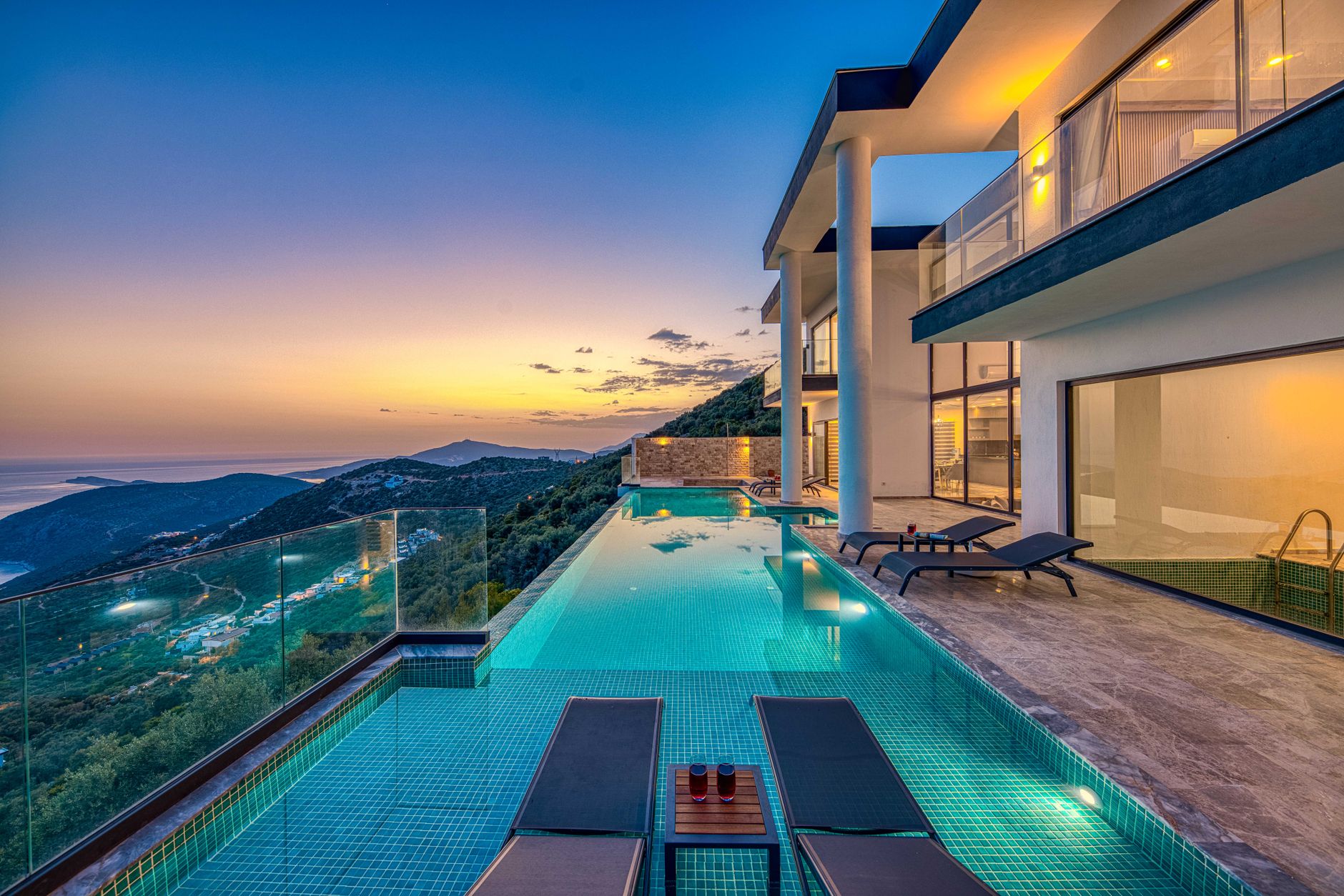 private white villa with infinity pool at sunset overlooking calm turquoise sea from luxury tropical resort