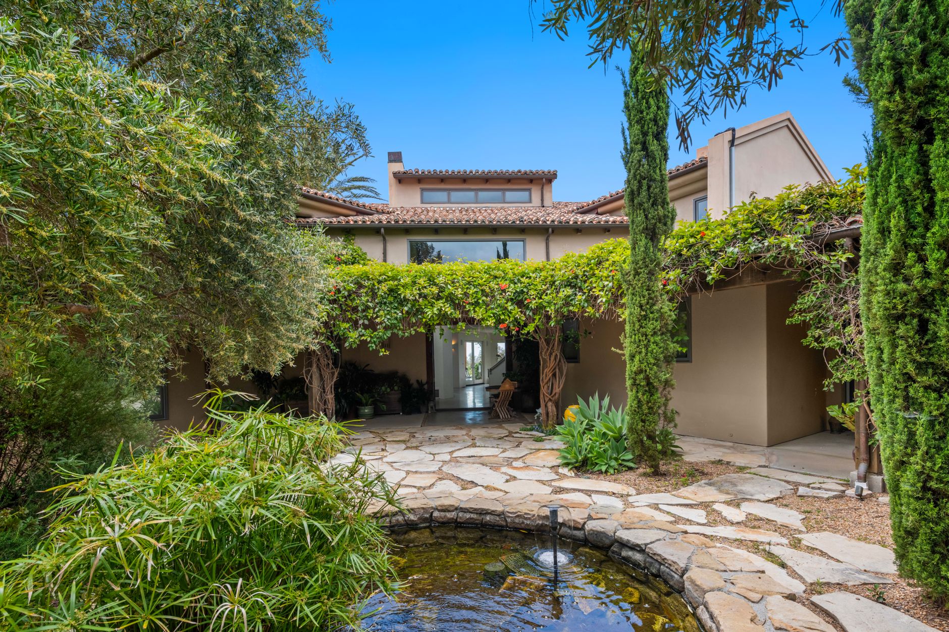 private villa courtyard garden with hand-laid limestone path water feature and curated tropical plantings at dusk