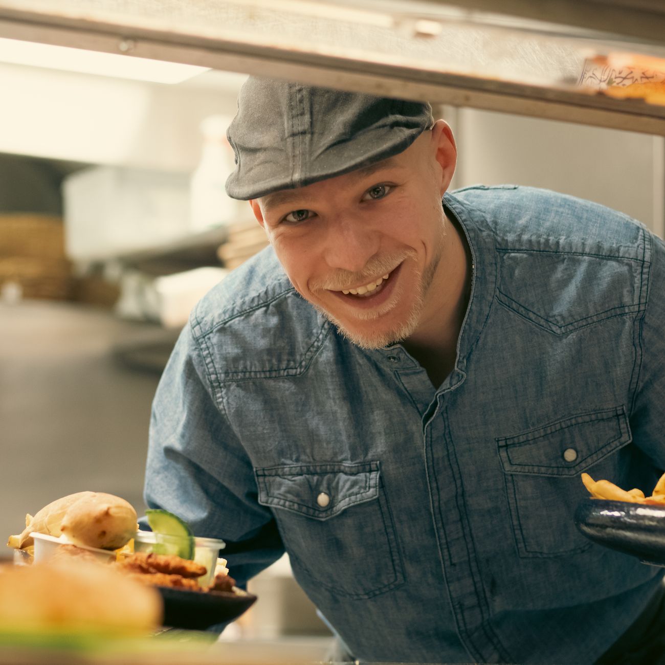 portrait of confident male executive chef in white jacket standing in open-air kitchen with tropical garden behind