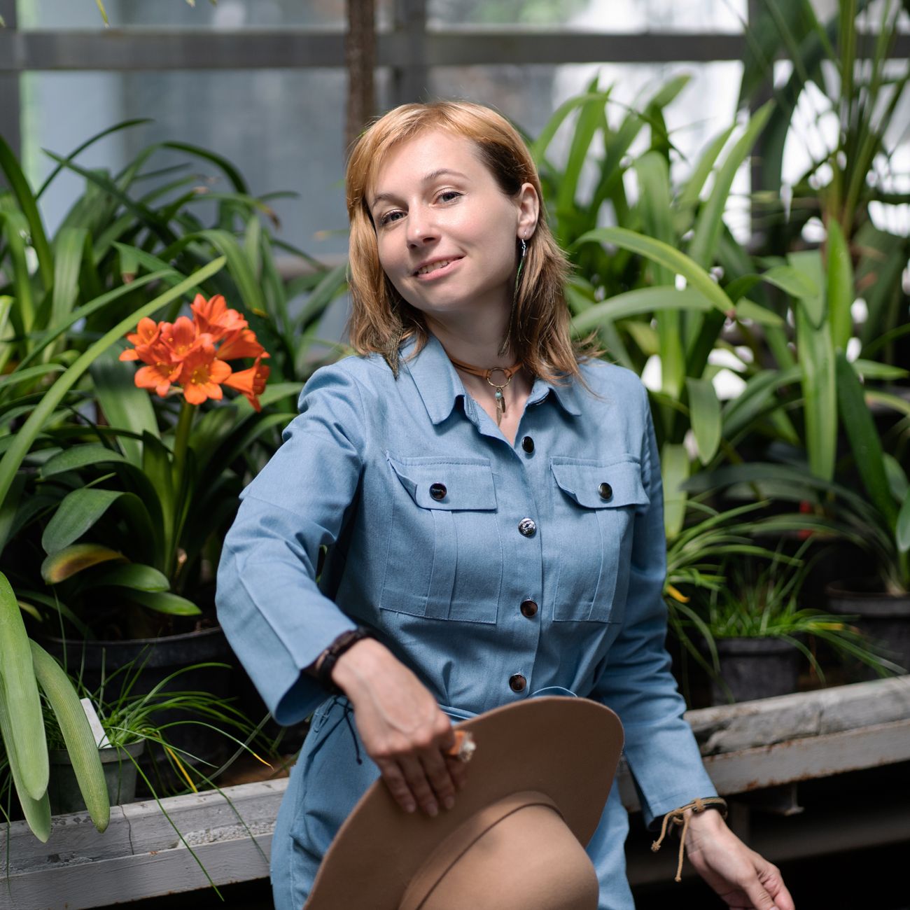portrait of calm female wellness director in spa uniform surrounded by tropical flowers and soft ambient light
